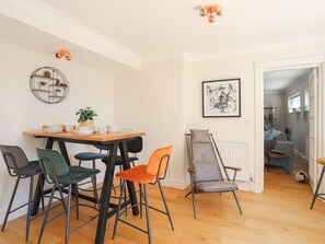 A dining area with a wooden table, four chairs, and a radiator. - Y Goedwig (Ty Croes)