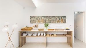 A modern kitchen with a wooden countertop, white cabinets, and a large decorative wall piece. - 2502 B&B Villa Eragea - Camere Standard by Barbarhouse (Matino)