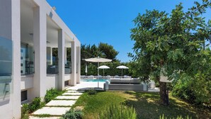 A modern outdoor pool area with a clear blue sky, a well-maintained lawn, and a seating area with umbrellas. - 2502 B&B Villa Eragea - Camere Standard by Barbarhouse (Matino)