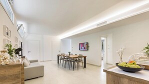 A modern living room with a dining area, a kitchen counter with fruits, and a TV on the wall. - 2502 B&B Villa Eragea - Camere Standard by Barbarhouse (Matino)
