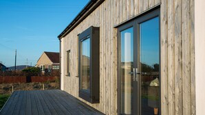 Una casa moderna de madera con amplios ventanales correderos y una terraza de madera.