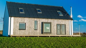 Una casa de madera con techo inclinado y tres ventanas.