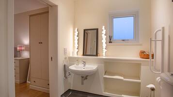 A modern bathroom with a vanity, sink, mirror, and toilet.