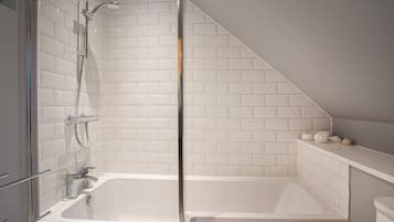A modern bathroom with a glass-enclosed shower, a white bathtub, and a tiled wall.