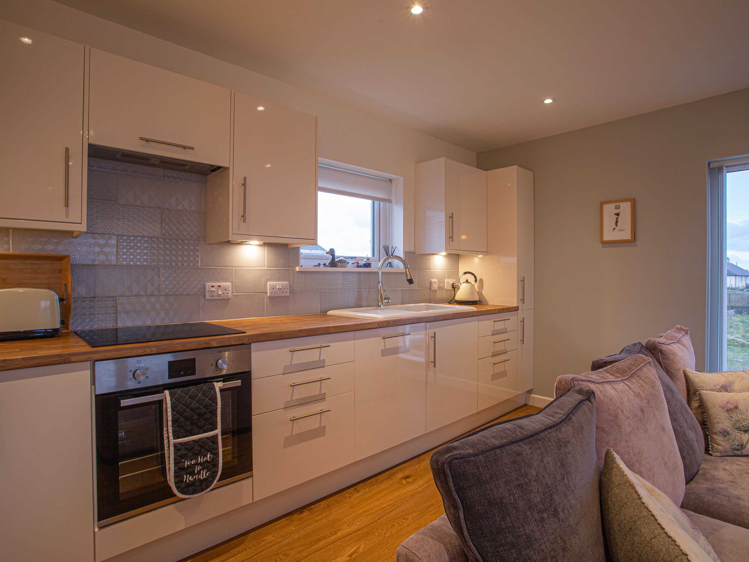 A modern kitchen with a built-in oven, a window above the sink, and a wooden countertop.