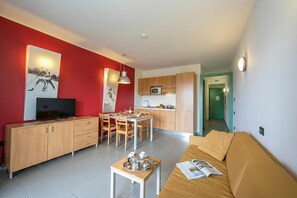 Un soggiorno moderno con un divano, una TV e un'area pranzo con tavolo e sedie.