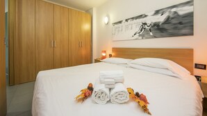 A hotel room with a large bed, wooden wardrobe, and a wall-mounted artwork. - Teleo 106 Ski In - Ski Out 50m, Sestriere, Italy (Sestriere)