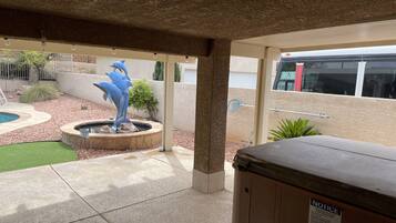 Relax by the small pool surrounded by a lush green border and a soothing fountain with a dolphin sculpture.