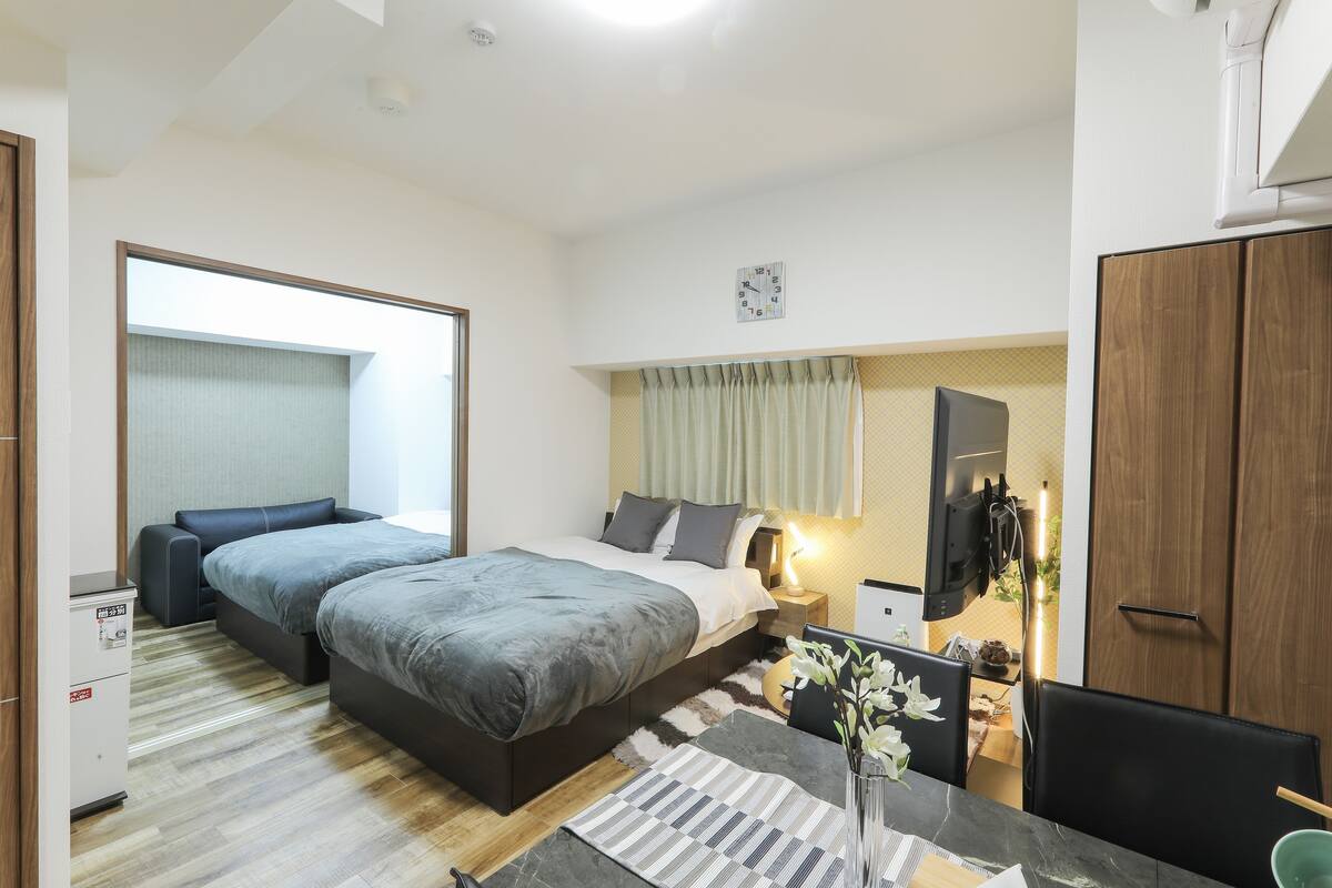 A modern bedroom with a bed, bedside table, TV, and a desk with a chair.