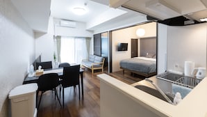 Una camera d'albergo moderna con zona pranzo, divano, letto e angolo cottura.