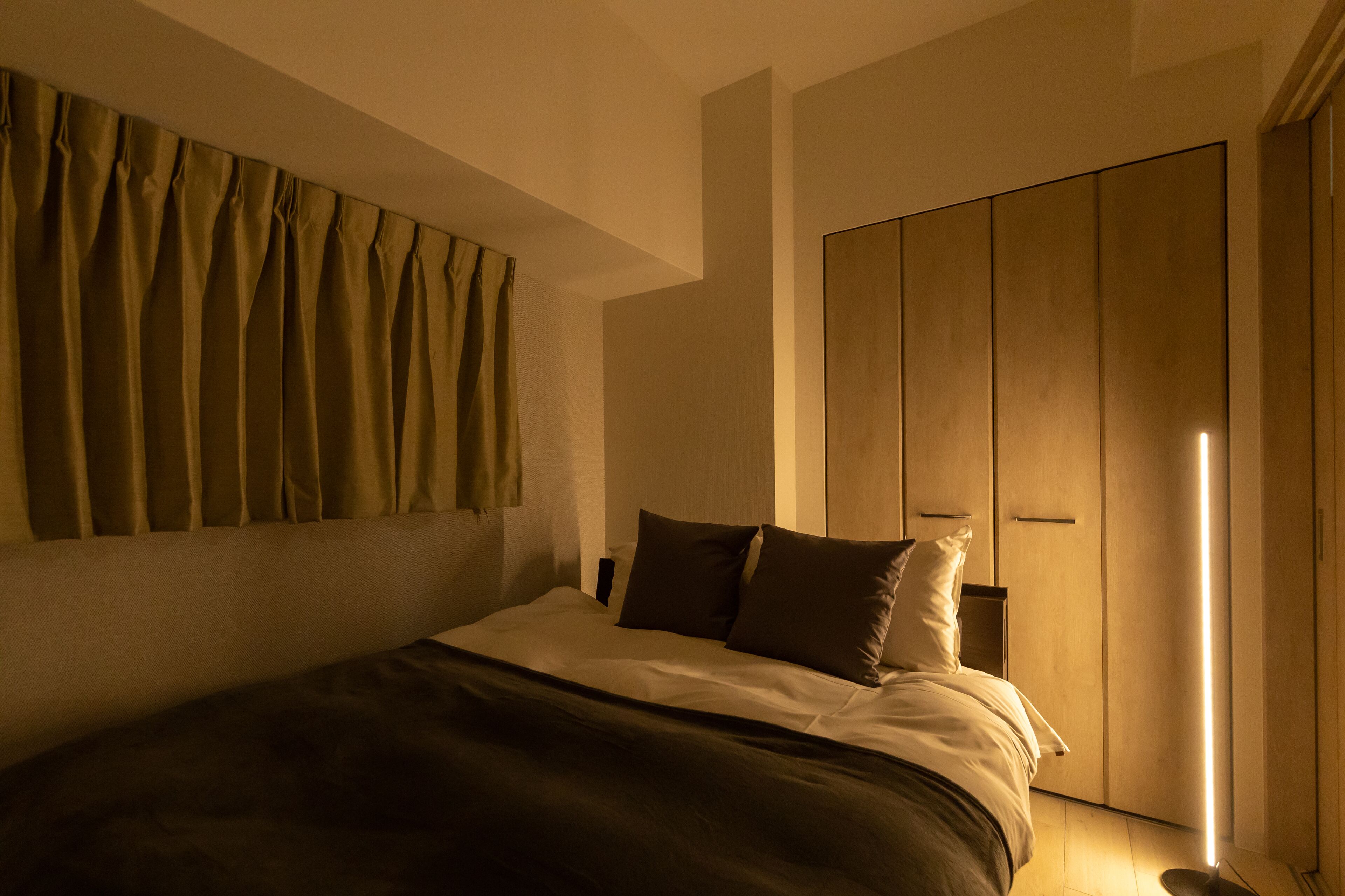 Une chambre à coucher avec un lit, une armoire et un rideau.