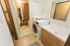 Ein kleines Badezimmer mit Waschmaschine, Waschbecken und Spiegel.