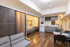 Ein kompakter Wohnraum mit Küchenzeile, Essbereich und Schlafzimmer mit Schiebetür.