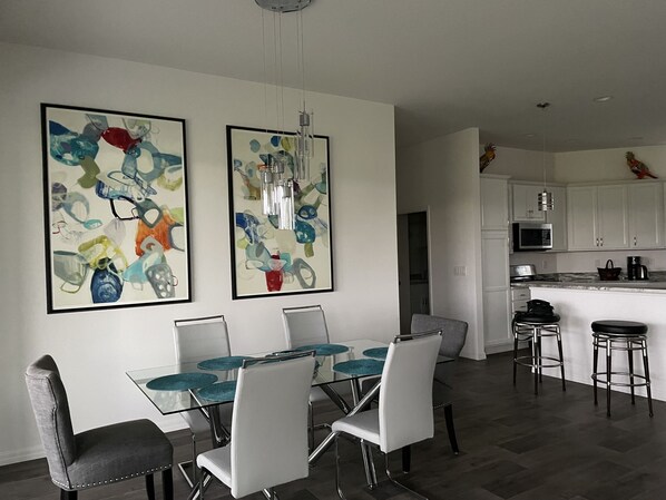 A modern kitchen with white cabinets, a stainless steel microwave, and a coffee maker.