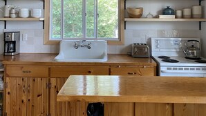 Eine Küche mit Holzschränken, einer weißen Spüle, einem Fenster und einem Herd.