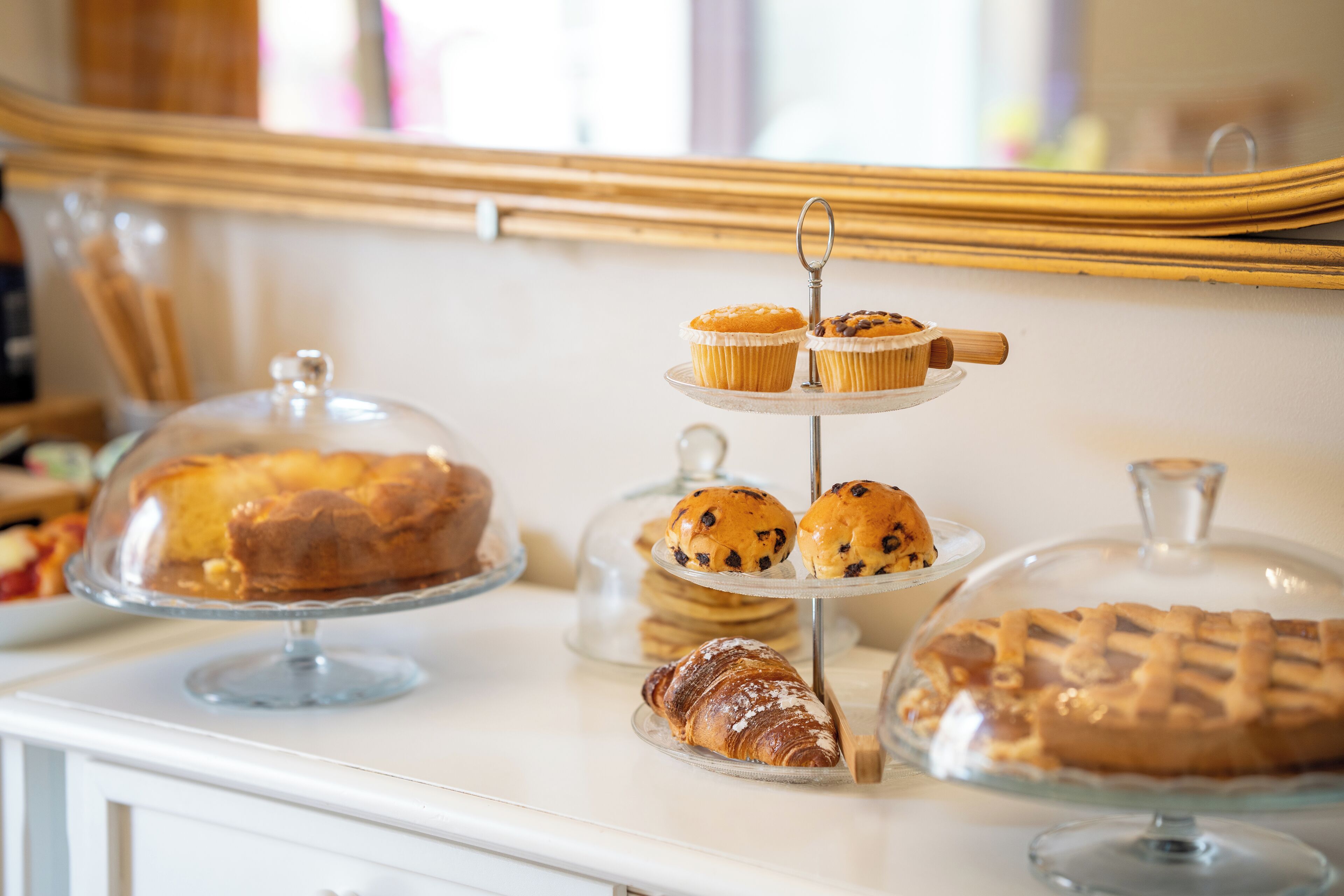 Une table de buffet proposant divers produits de boulangerie, notamment une miche de pain, des muffins et un croissant.