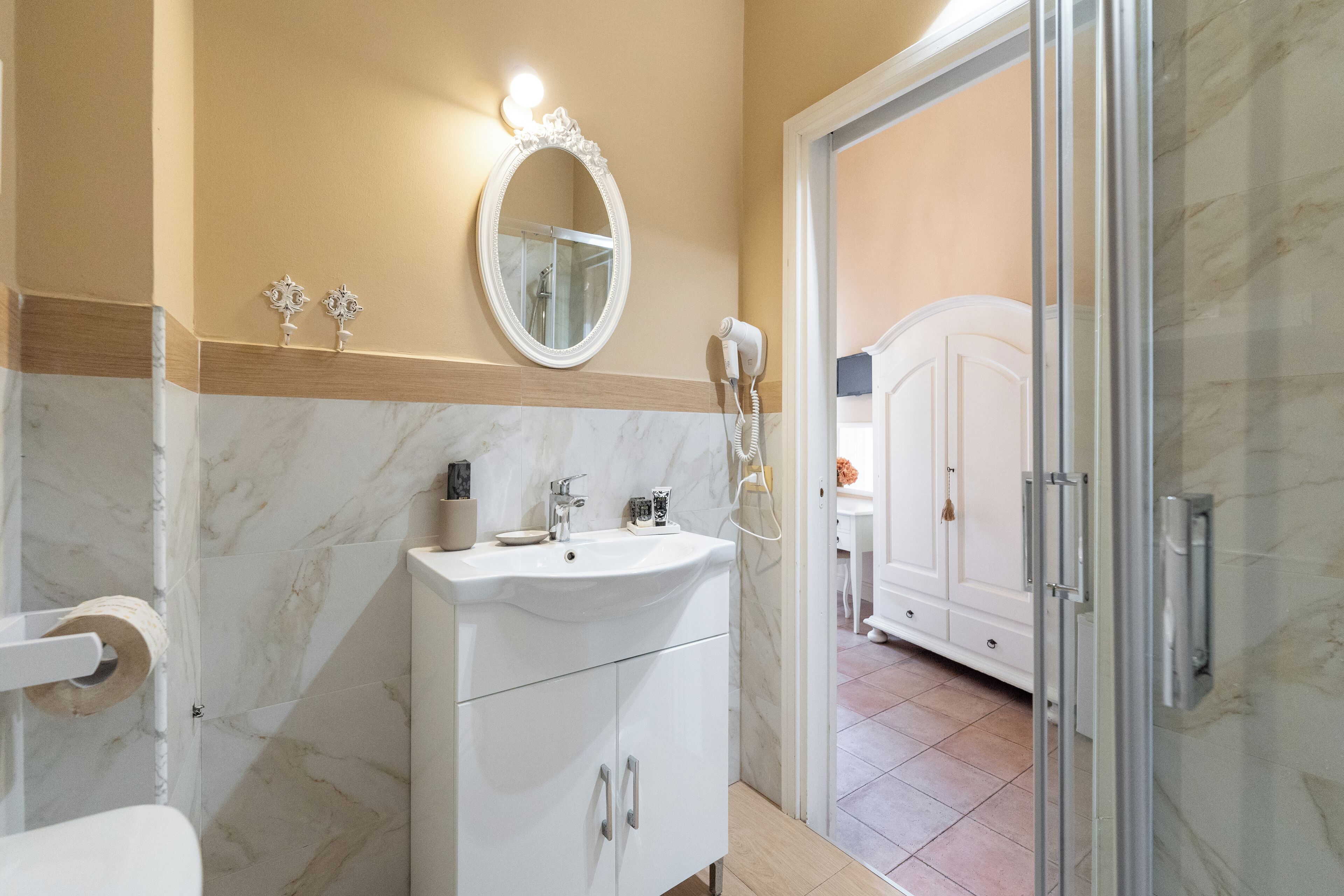 A bathroom with a white sink, mirror, and a hairdryer on the wall.