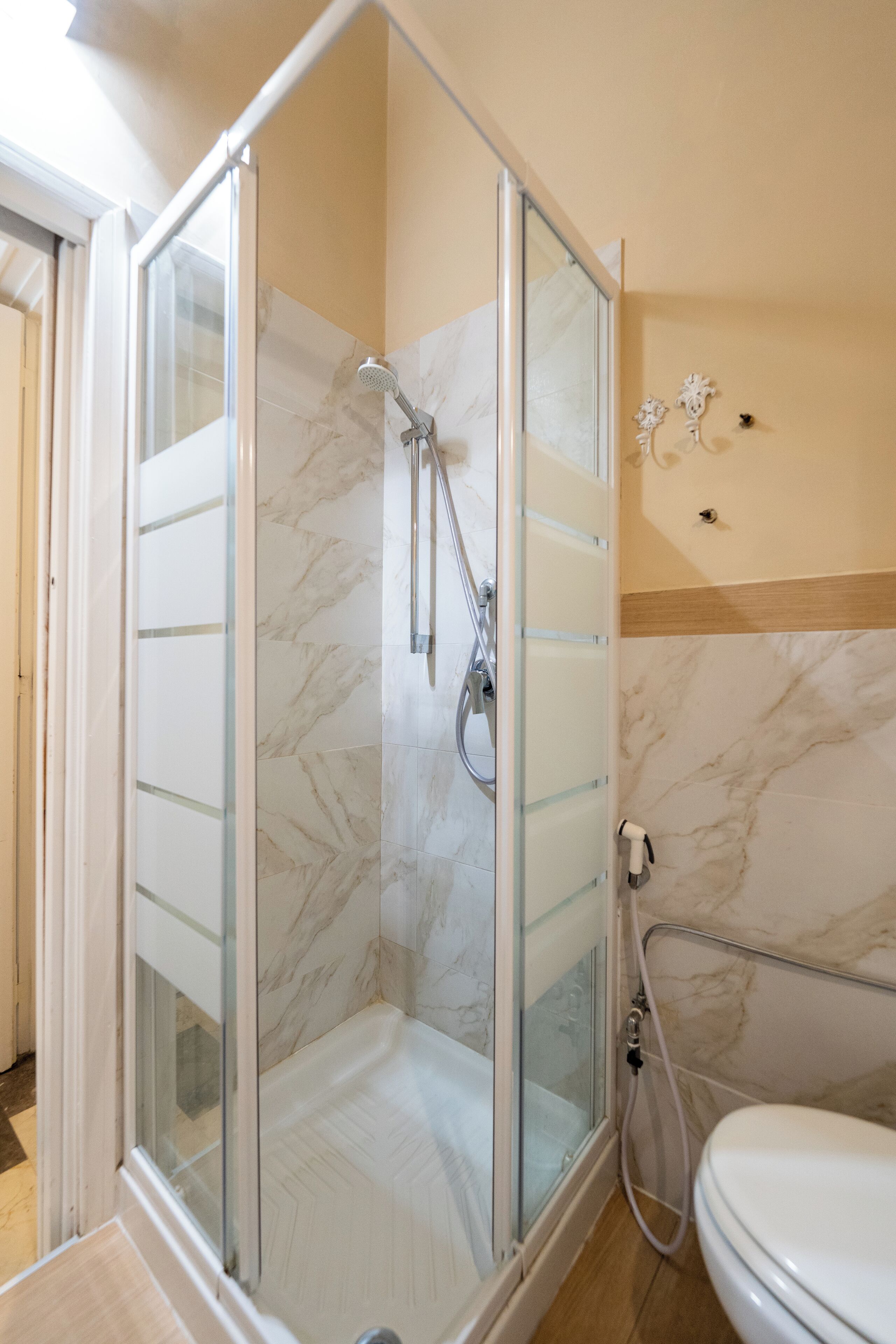 Ein modernes Badezimmer mit einer gläsernen Duschkabine, einer weißen Toilette und Marmorwänden.