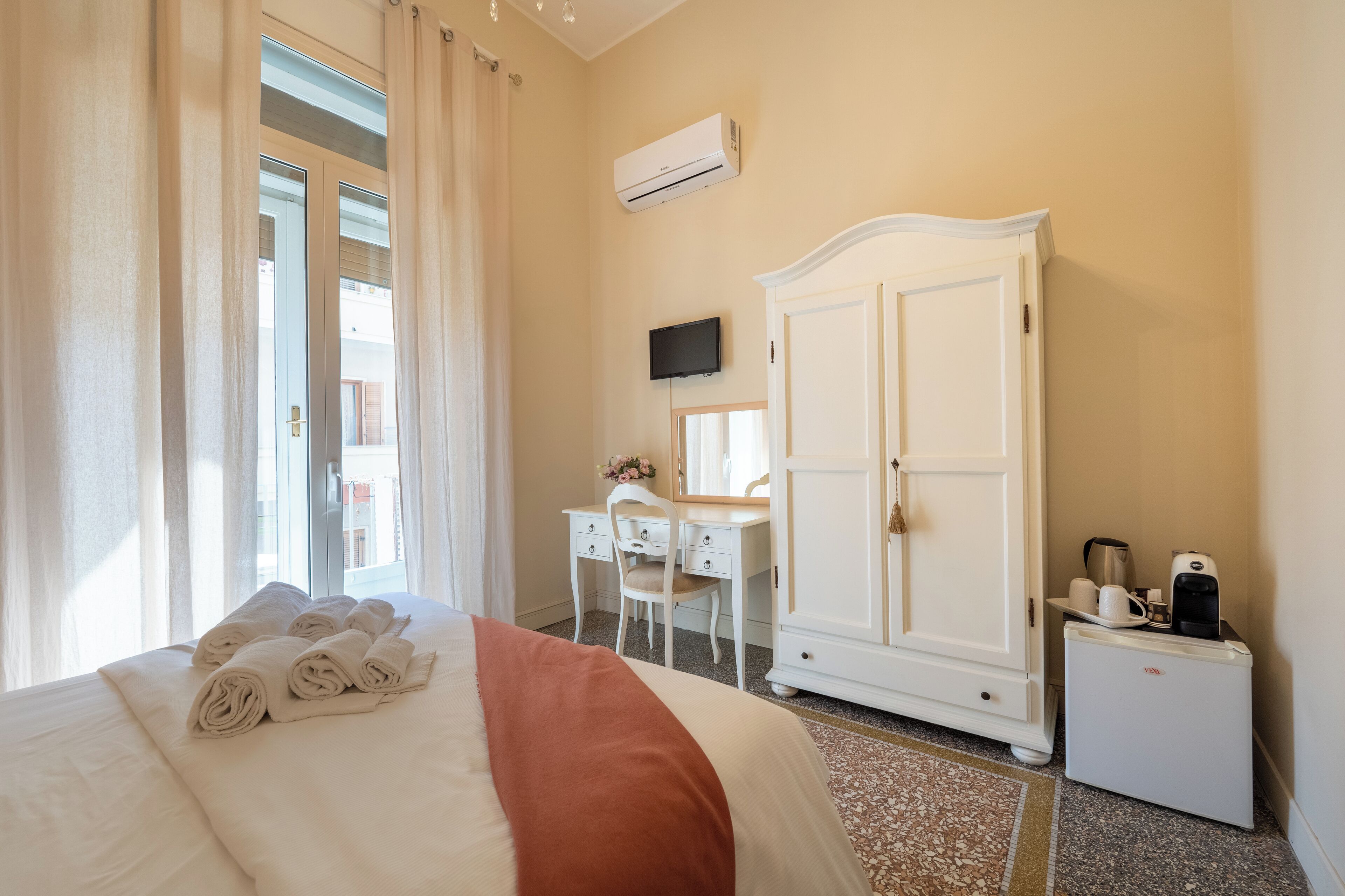 Een hotelkamer met een bed, bureau, kledingkast en koffieapparaat.