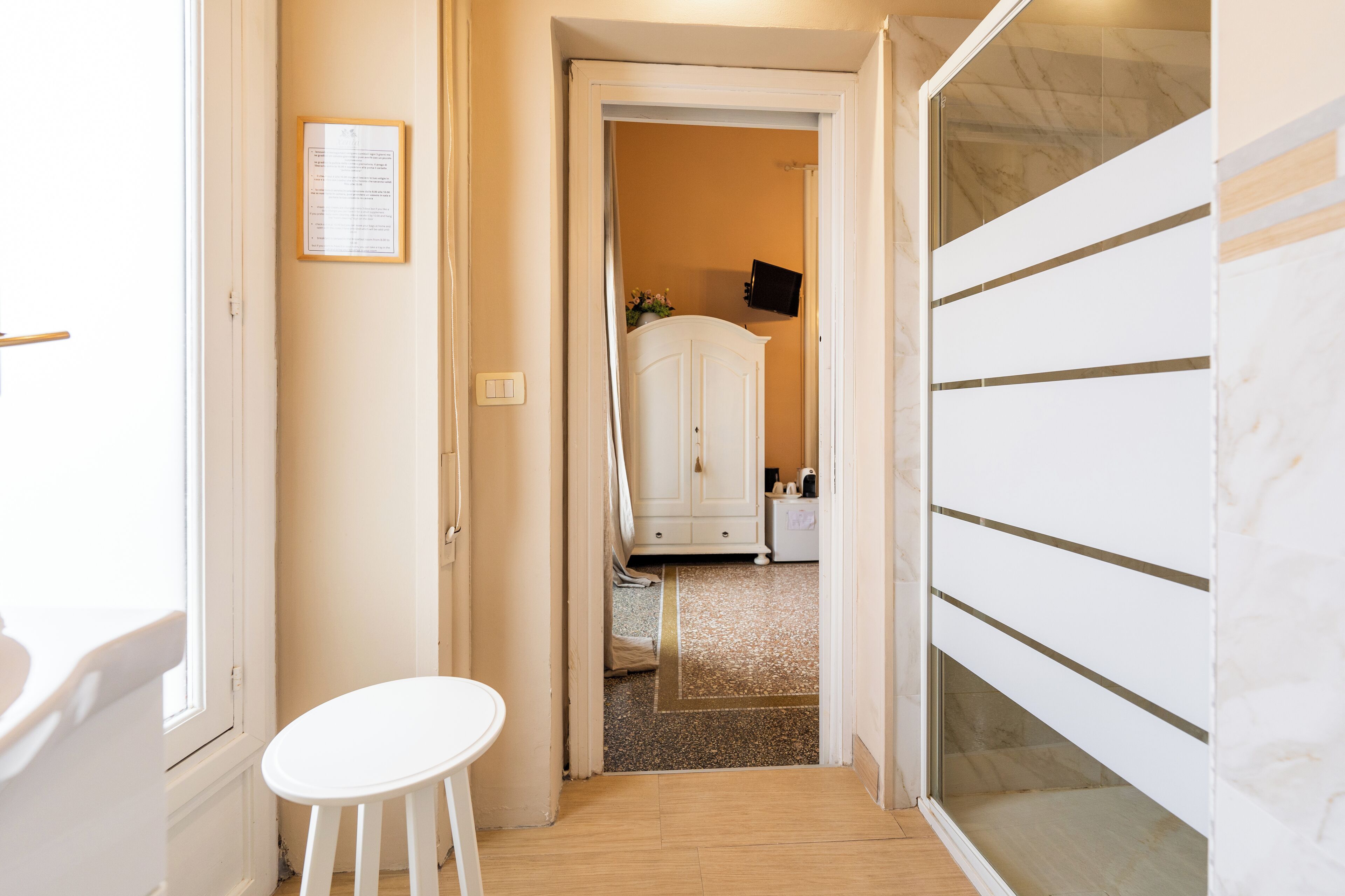 A narrow hallway with a white door leading to a room with a white cabinet and a small table.