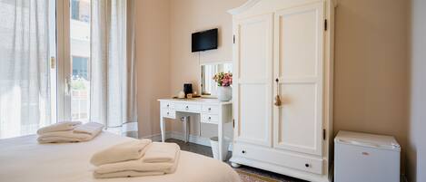 Ein Hotelzimmer mit Bett, Schreibtisch, Kleiderschrank, Fernseher und kleinem Kühlschrank.