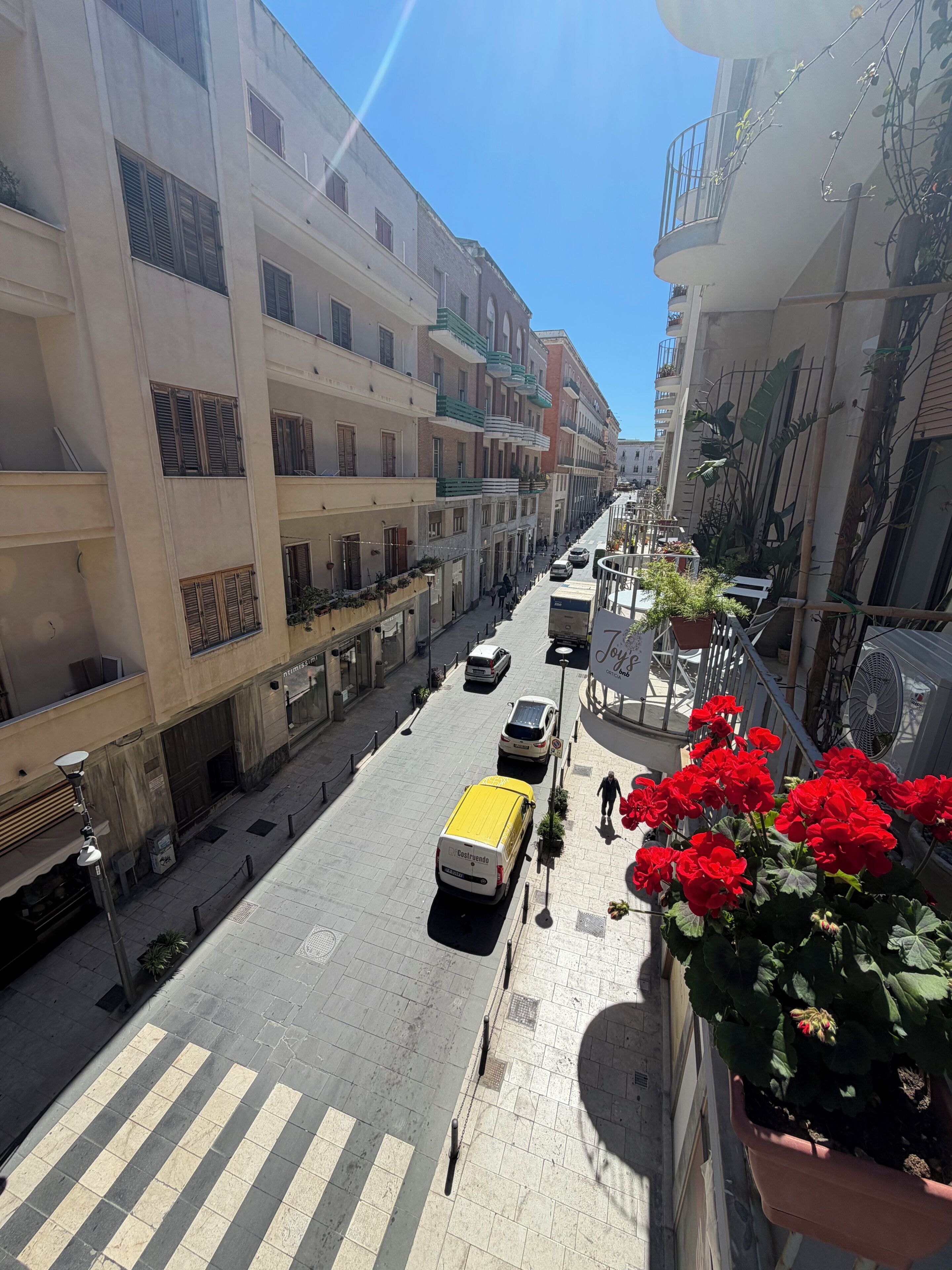 A street view with multi-story buildings, a pedestrian crossing, and parked vehicles.