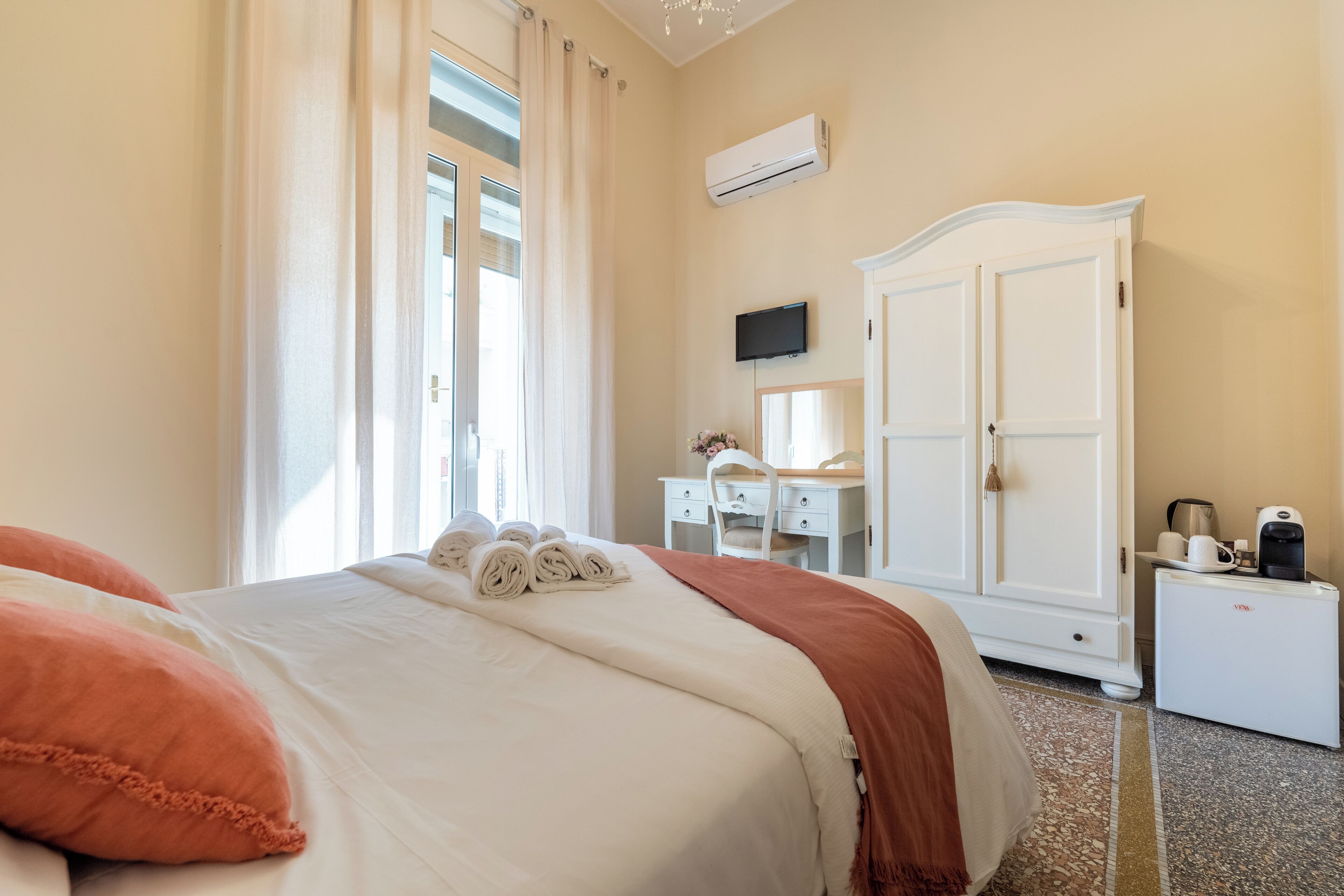 A hotel room with a bed, a desk, a wardrobe, and a TV.