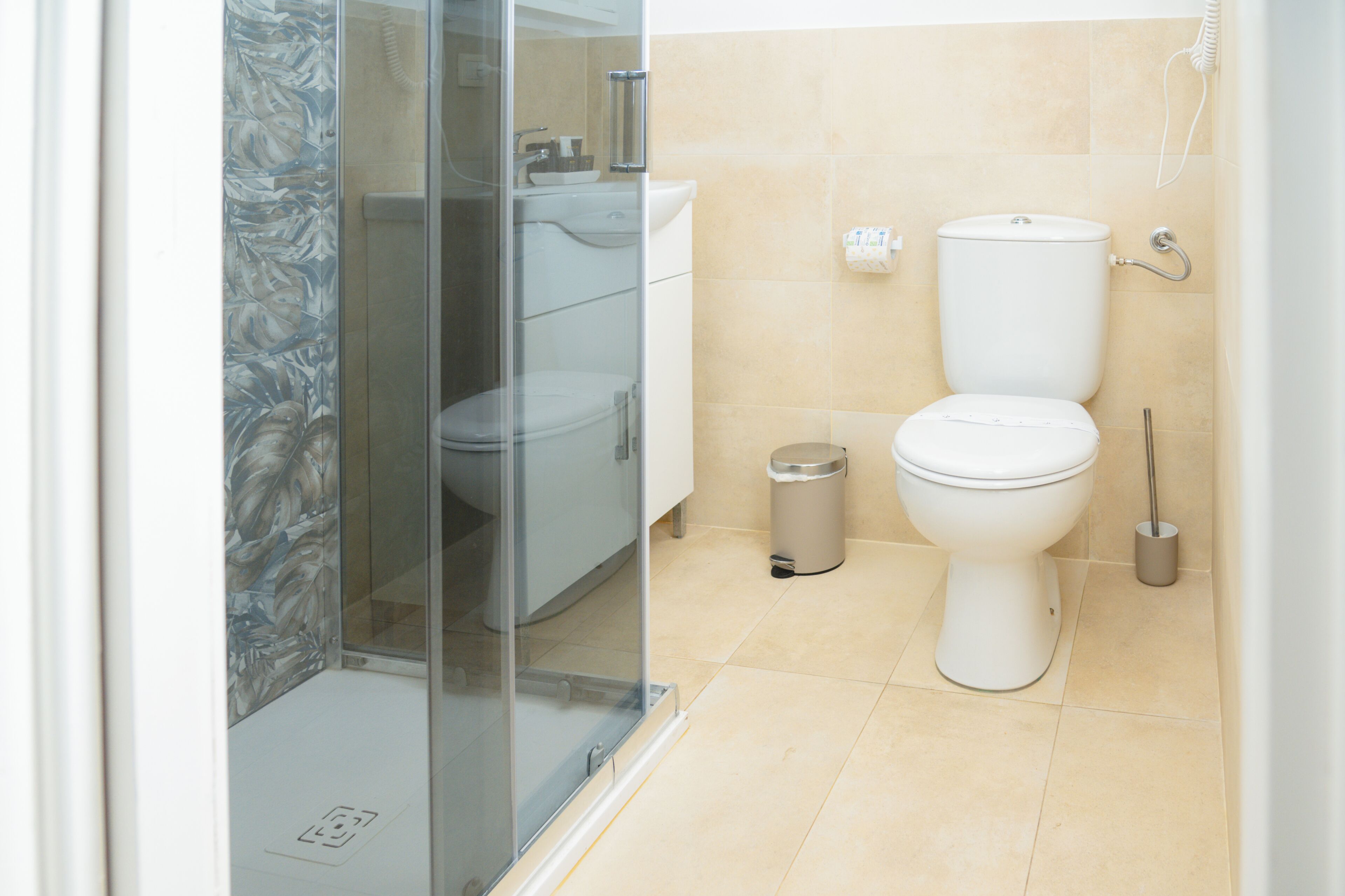 A bathroom with a toilet, bidet, and glass shower enclosure.