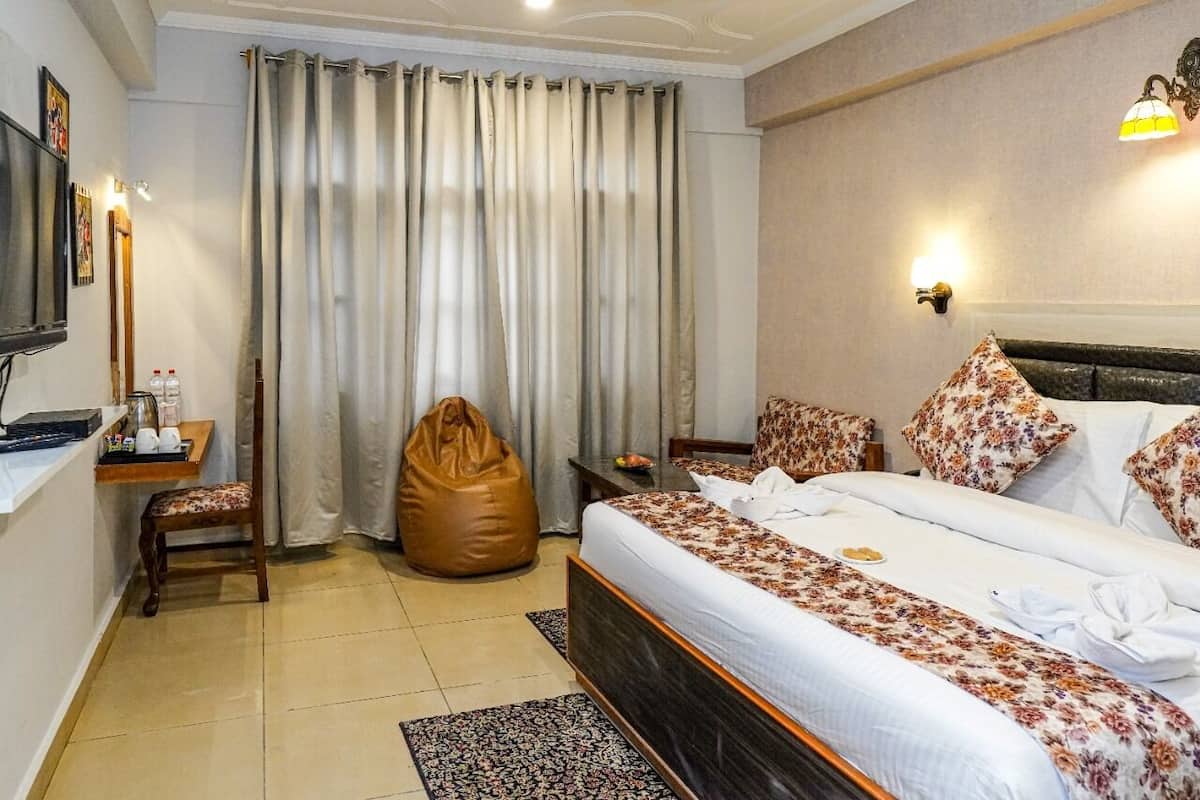 A hotel room with a bed, a desk with a chair, a television, and a large bean bag chair.