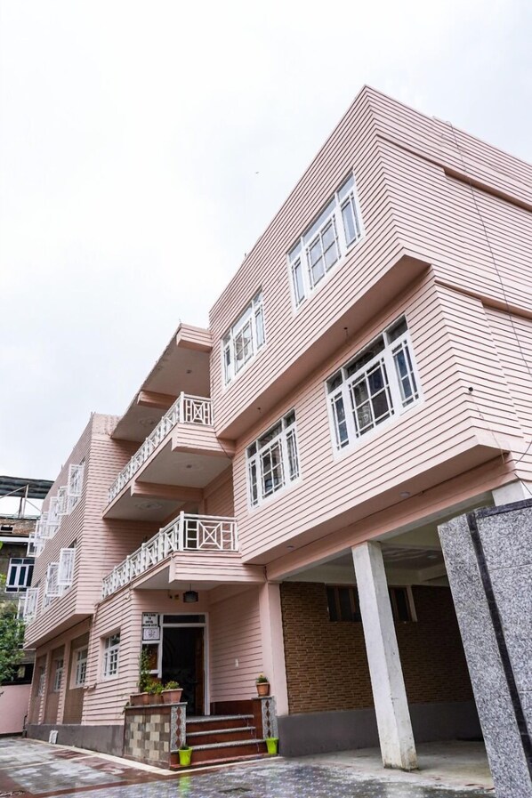 Un edificio de varios pisos con fachada rosa, balcones y base de ladrillo.