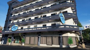 Un hotel de varios pisos con balcones, unidades de aire acondicionado y un letrero que indica que es The INNS by The Oriental Bacolod.