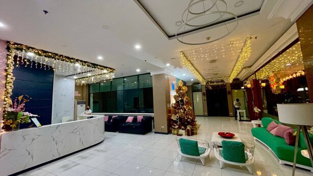 Un vestíbulo de hotel con mostrador de recepción, zona de estar y un árbol de Navidad.