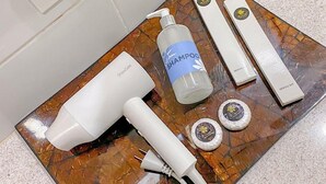 Una encimera de baño con un secador de pelo, una botella de champú, un kit de higiene bucal y dos recipientes redondos.