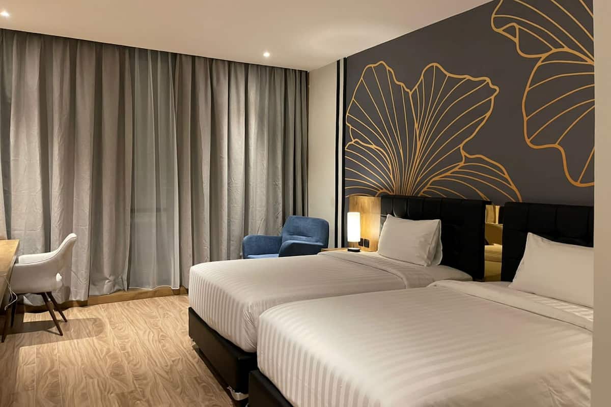 Une chambre d’hôtel avec deux lits, un bureau, une chaise et un grand mur décoratif.