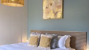 Ein Schlafzimmer mit Bett, Nachttisch, Wandlampe und einem Gemälde.