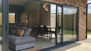 Ein modernes Haus mit einer Glastür, die zu einem Essbereich mit Tisch und Stühlen führt.