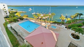 Ein Resort mit einem großen Schwimmbecken, einem kleineren Pool und Blick auf den Hafen mit Booten.