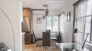 Une cuisine moderne avec un réfrigérateur en acier inoxydable, une table de salle à manger ronde entourée de chaises et un luminaire suspendu.