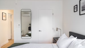 Une chambre d’hôtel moderne avec un grand lit, une table de chevet, un miroir et une porte.