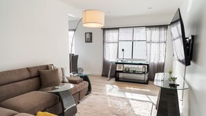 Un salon moderne avec un canapé marron, une table basse en verre et un téléviseur fixé au mur.