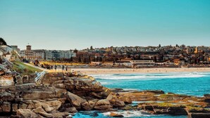 A coastal cityscape with a rocky shoreline, a beach, and a densely packed urban area in the background. - Cozy beachfront studio with aircon (North Bondi)