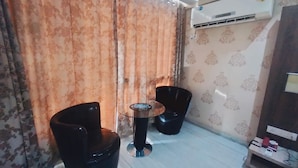 A small room with two black chairs, a small round table, and a wall-mounted air conditioner. - Heterosis (Udaipur)