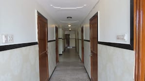 A long, narrow hallway with doors on both sides, a tiled floor, and recessed lighting on the ceiling. - Heterosis (Udaipur)