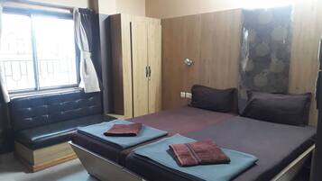 A room with a bed, a bench, a wardrobe, and a window with curtains.