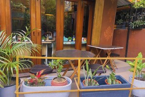 An outdoor seating area with a table and chairs, surrounded by potted plants. - The Kei Inn & Suites Hotel near Salt Lake (Bidhannagar)