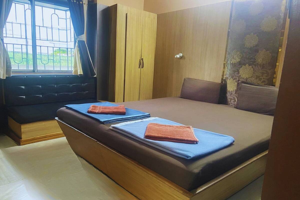 A bedroom with a bed, wooden wardrobe, and a window with curtains.