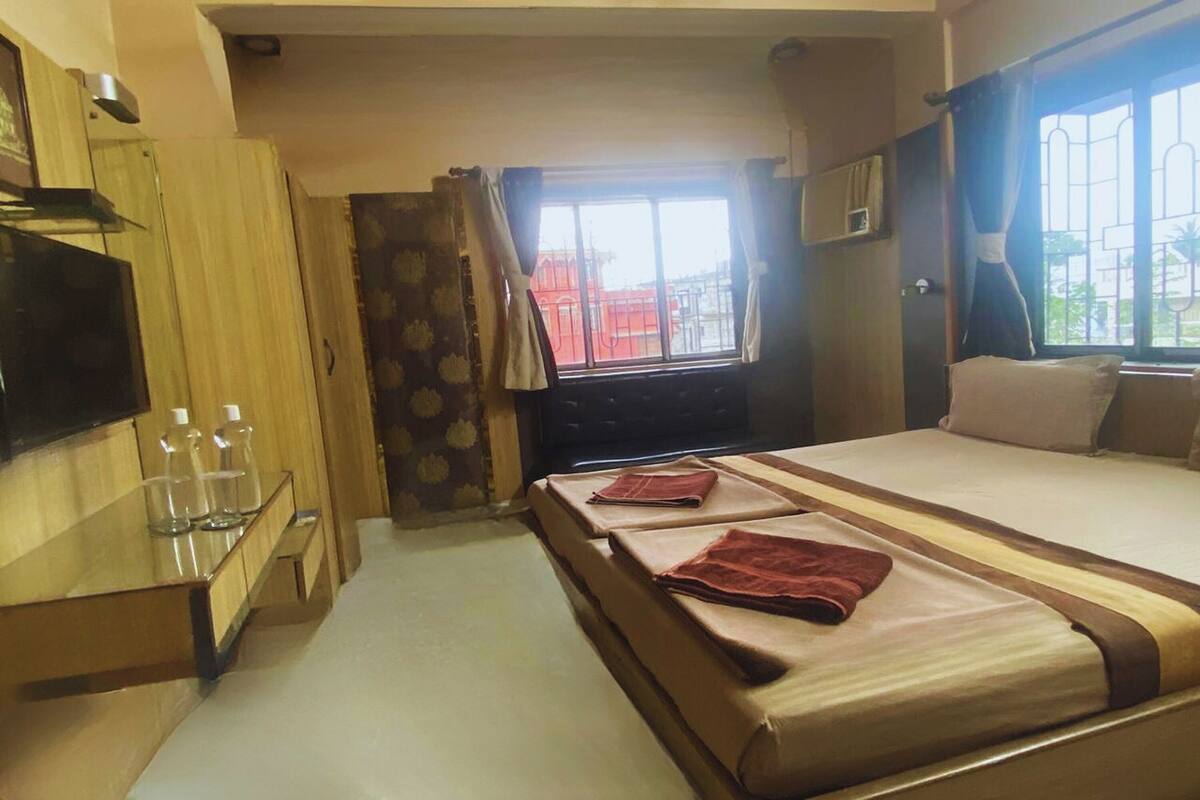 A hotel room with a bed, a TV, a desk with glasses, and a window with curtains.