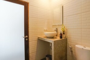 A bathroom with a white sink, a mirror, and a toilet. - D'Meten Guest House Canggu (Canggu)