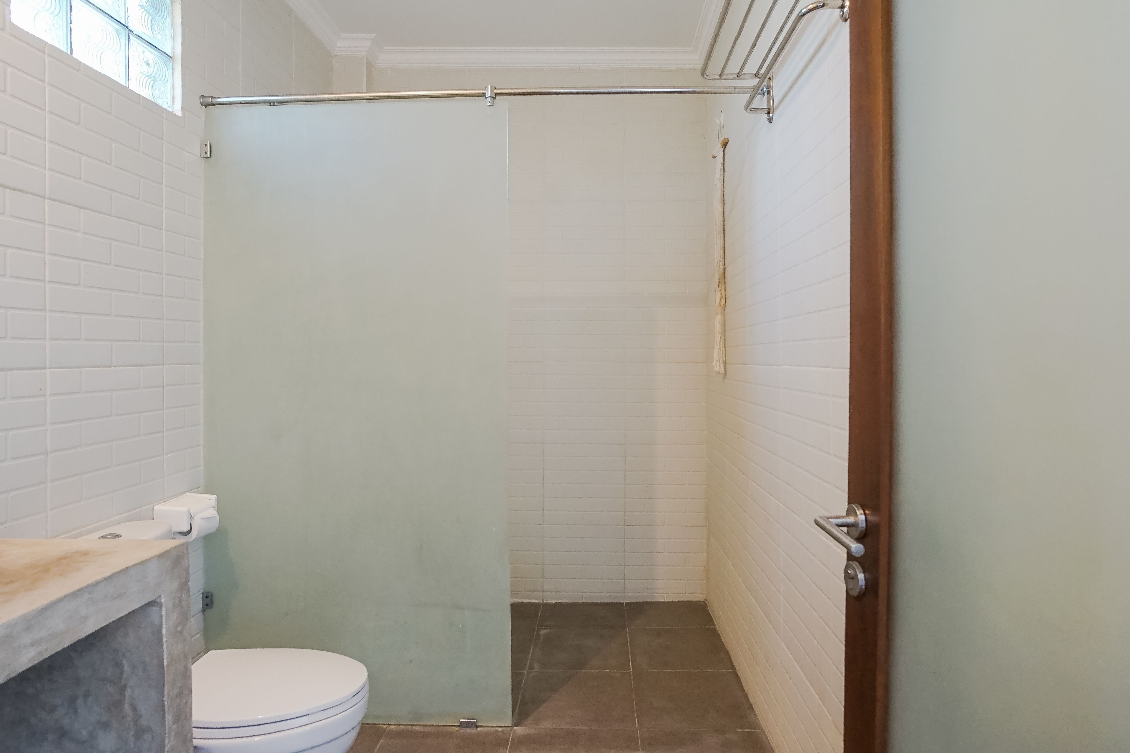 Une salle de bain comprenant des toilettes, un espace douche et un sol carrelé.