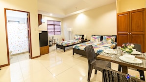 A hotel room with two beds, a dining table set for four, and a bathroom visible through an open door. - Verjandel Residences (Quezon City)